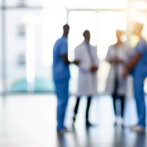 Man smiling while sitting on the couch reading from a tablet and holding a green coffee mug.